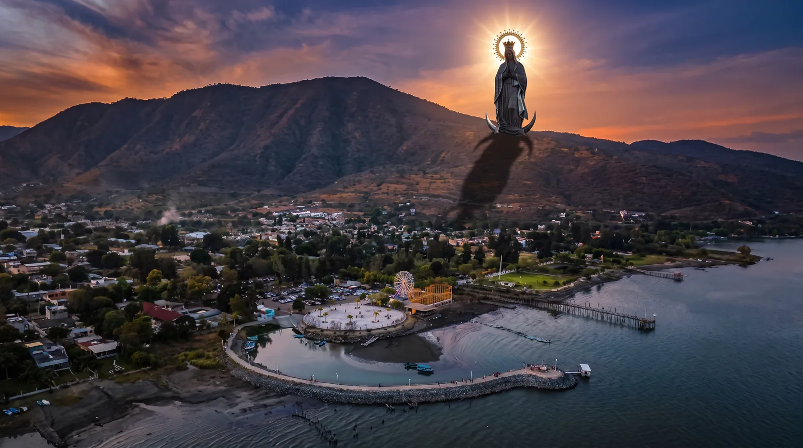 Vista de un poblado de Jalisco y sus montañas con una figura mariana iluminada sobre el cerro.